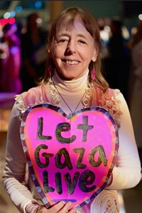 activist medea benjamin holding a pink heart sign that reads, 'let gaza live'.
